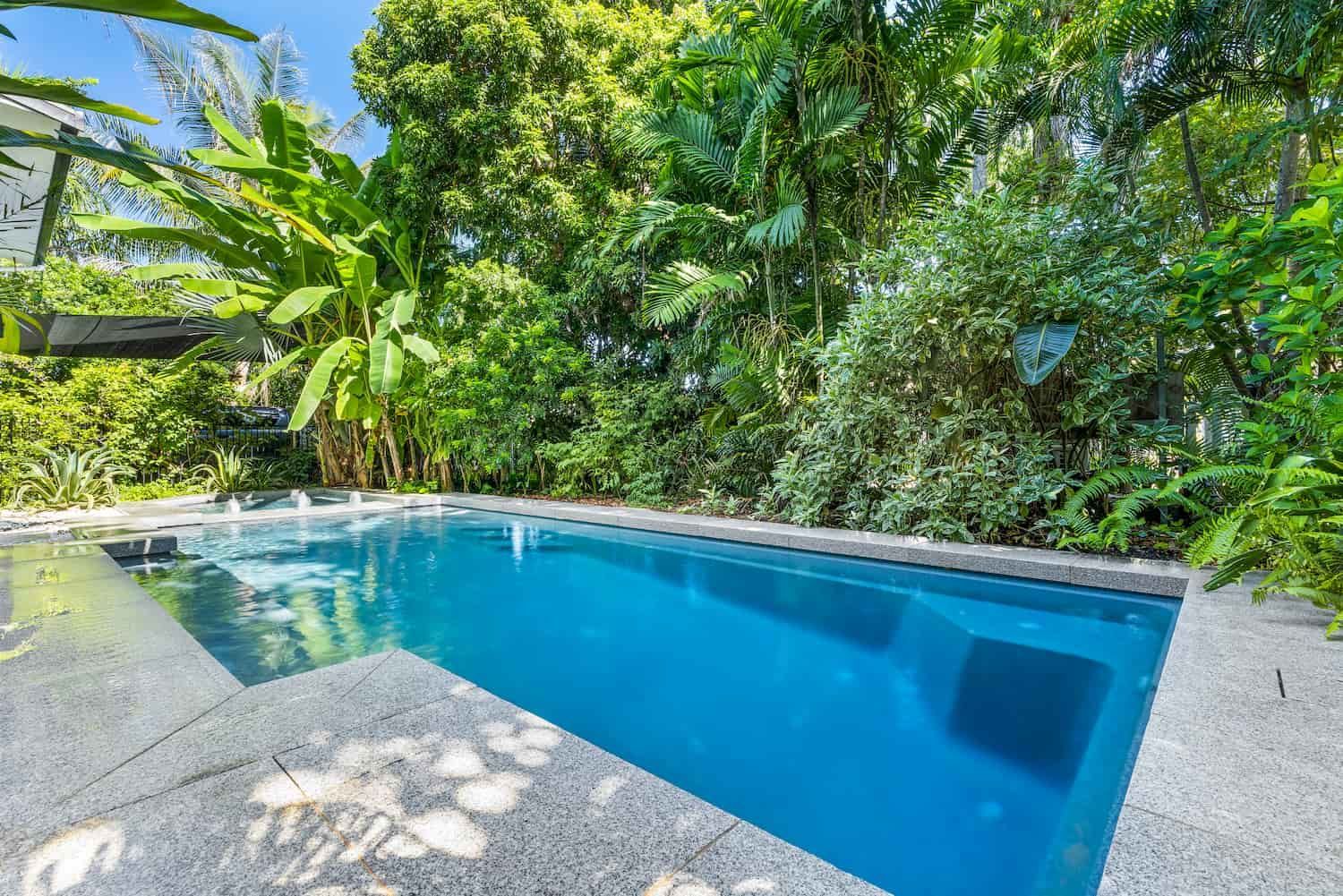 A Large Swimming Pool Surrounded by Trees and Bushes in a Backyard — Pooltech NT In Alawa, NT