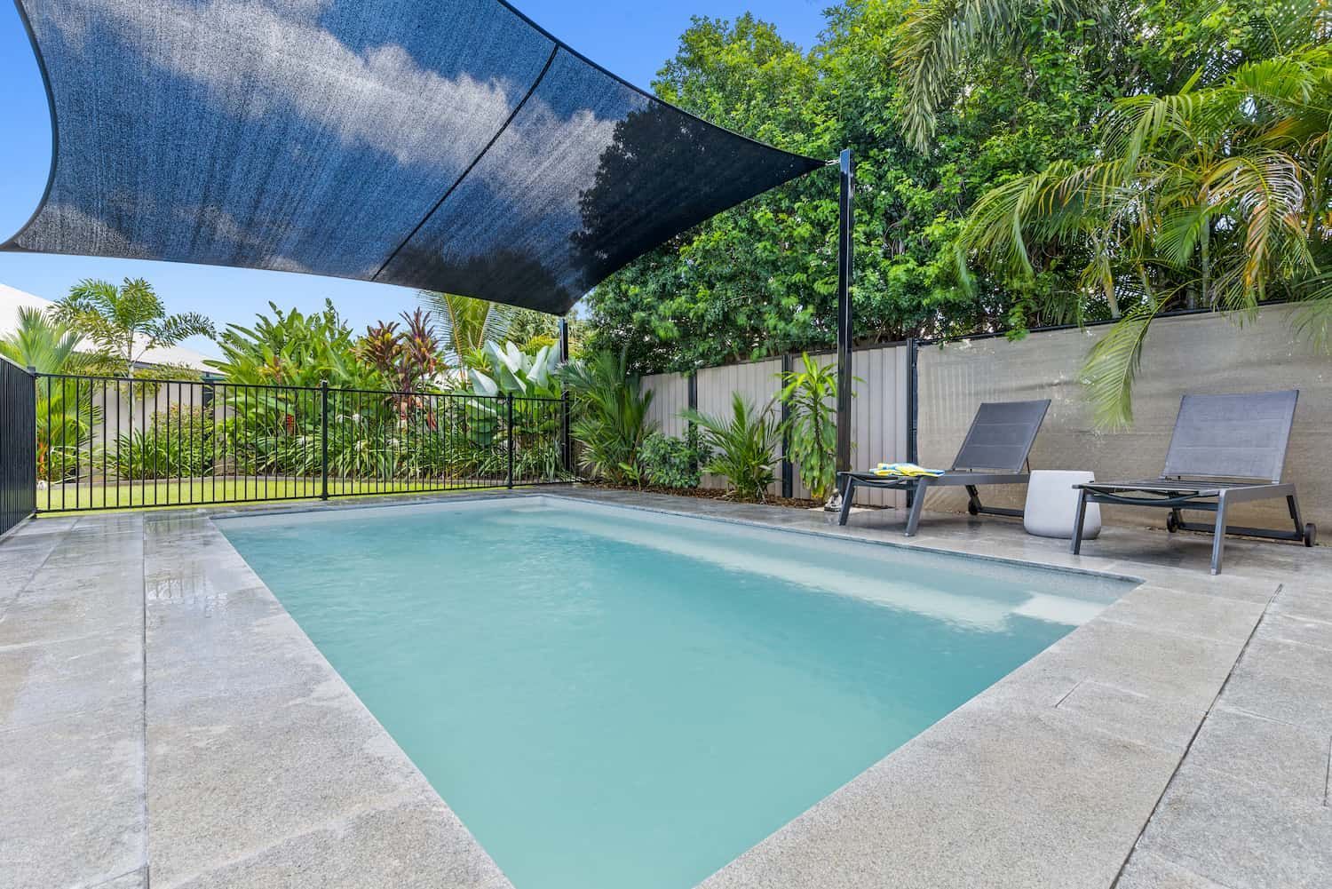 A Large Swimming Pool in a Backyard With a Black Umbrella Over It — Pooltech NT In Alawa, NT
