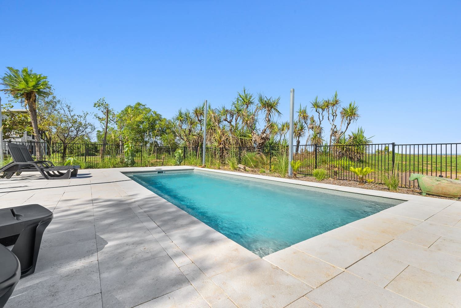A Large Swimming Pool is Surrounded by Trees and a Fence — Pooltech NT In Alawa, NT
