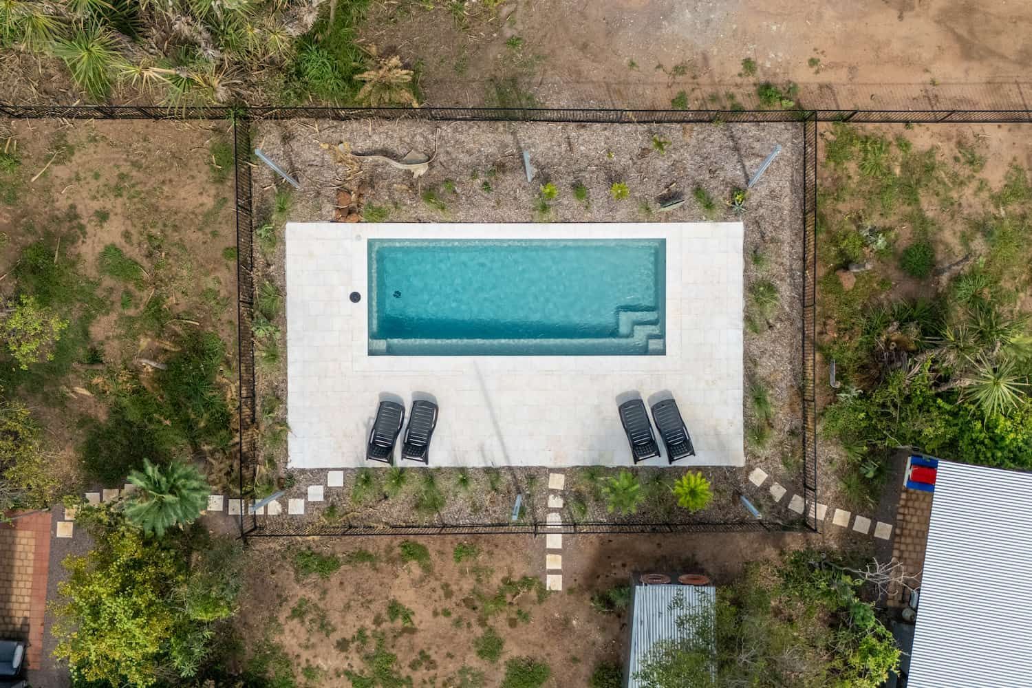 An Aerial View of a Large Swimming Pool Surrounded by Trees and a Fence — Pooltech NT In Alawa, NT