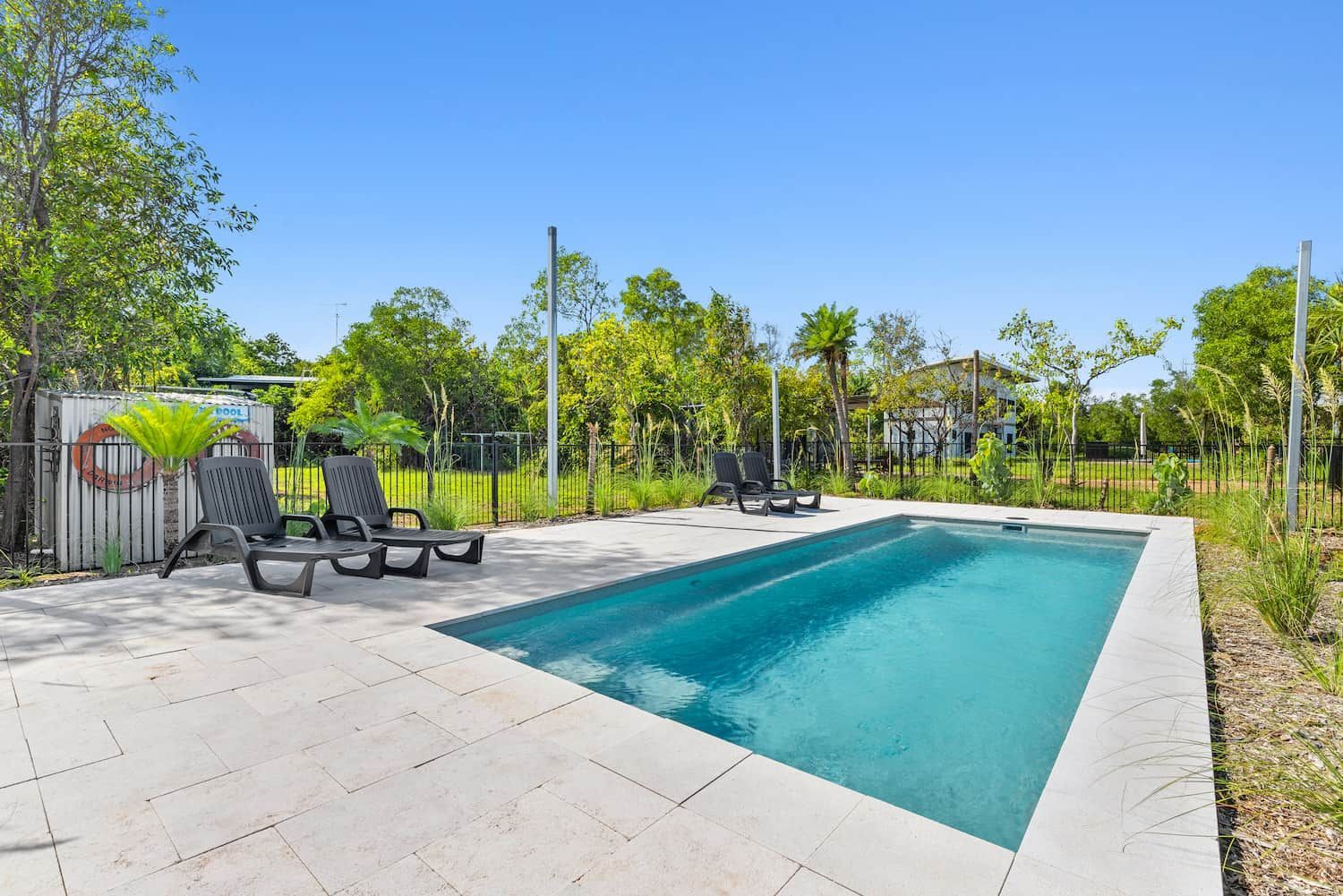 A Large Swimming Pool is Surrounded by Chairs and Trees — Pooltech NT In Alawa, NT