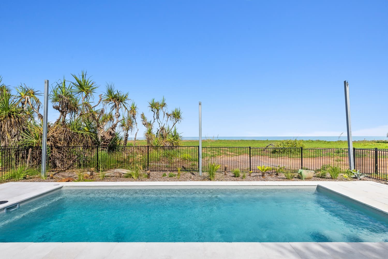A Large Swimming Pool With a Fence Around It and a View of the Ocean — Pooltech NT In Alawa, NT
