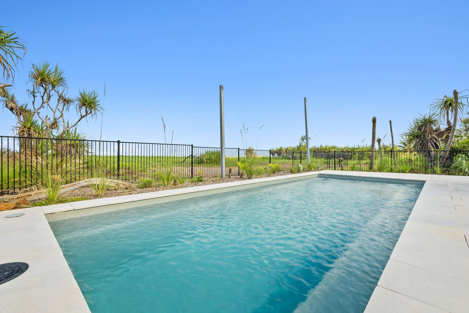 A Large Swimming Pool Surrounded by a Fence and Trees on a Sunny Day — Pooltech NT In Alawa, NT