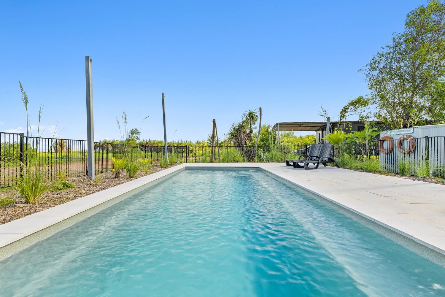 A Large Swimming Pool Surrounded by a Fence and Chairs — Pooltech NT In Alawa, NT
