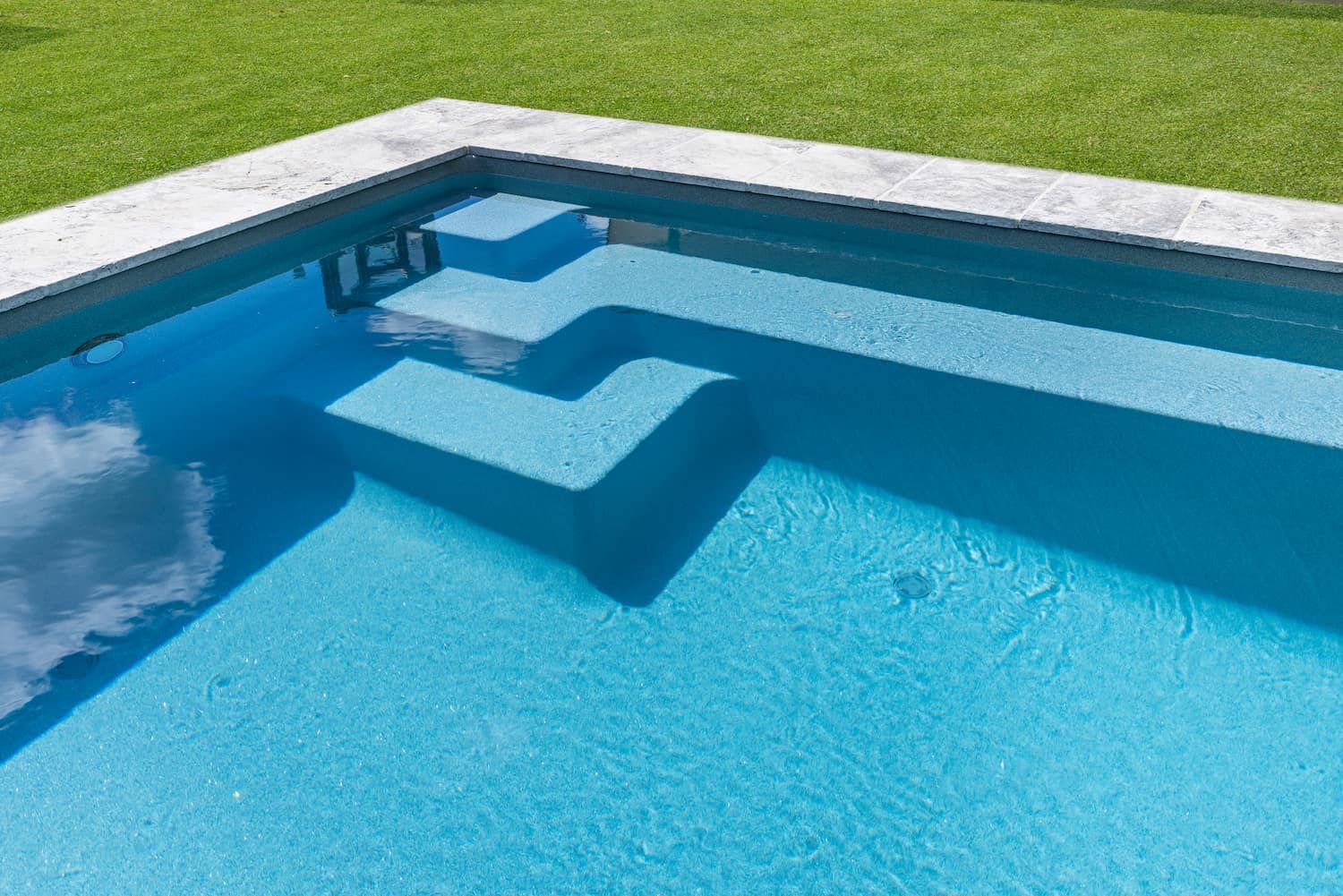 A Swimming Pool With Steps Leading Into It and a Reflection of Clouds in the Water — Pooltech NT In Alawa, NT