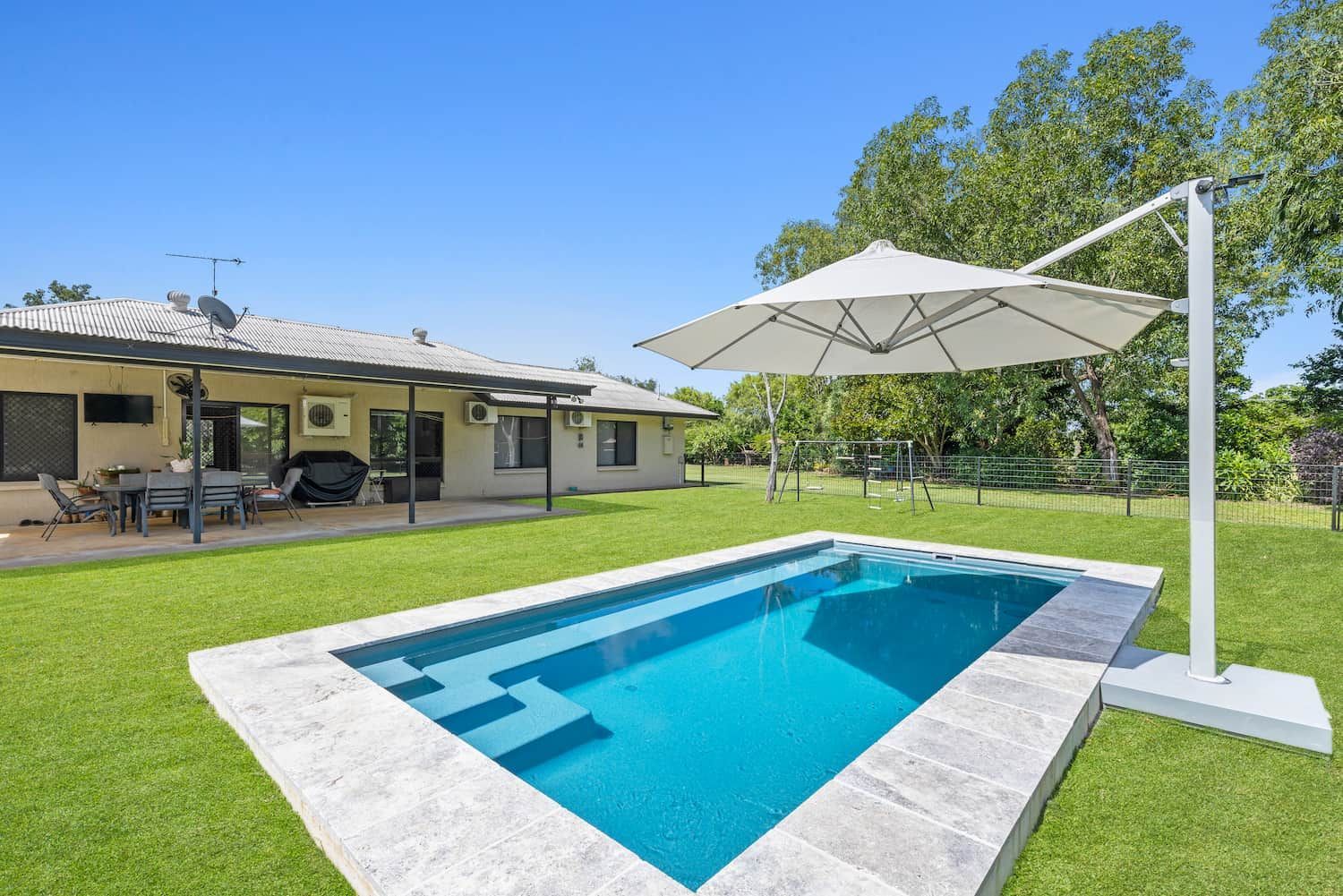 A Large Swimming Pool With a White Umbrella in the Middle — Pooltech NT In Alawa, NT