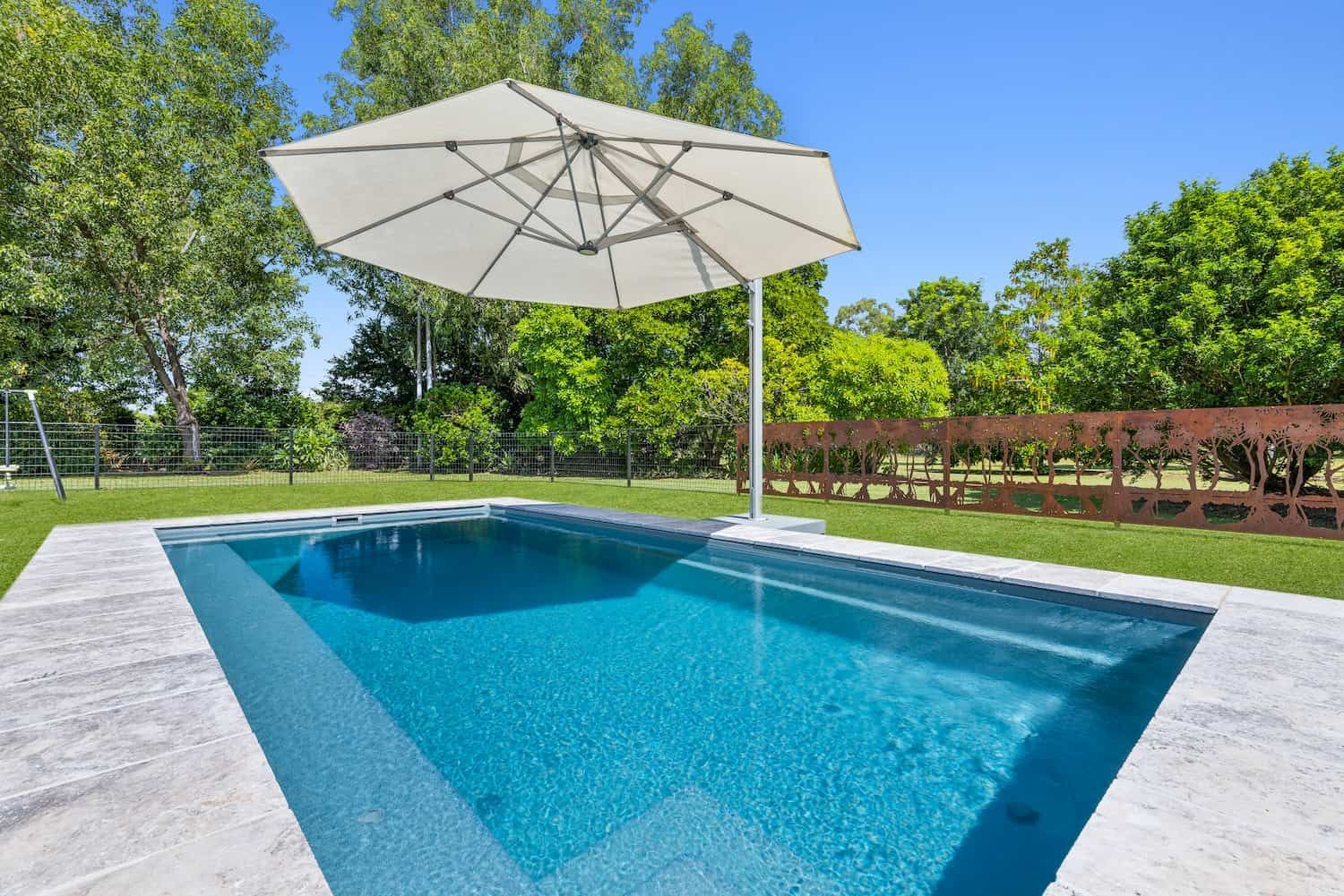 A Large Swimming Pool With a White Umbrella in the Middle — Pooltech NT In Alawa, NT