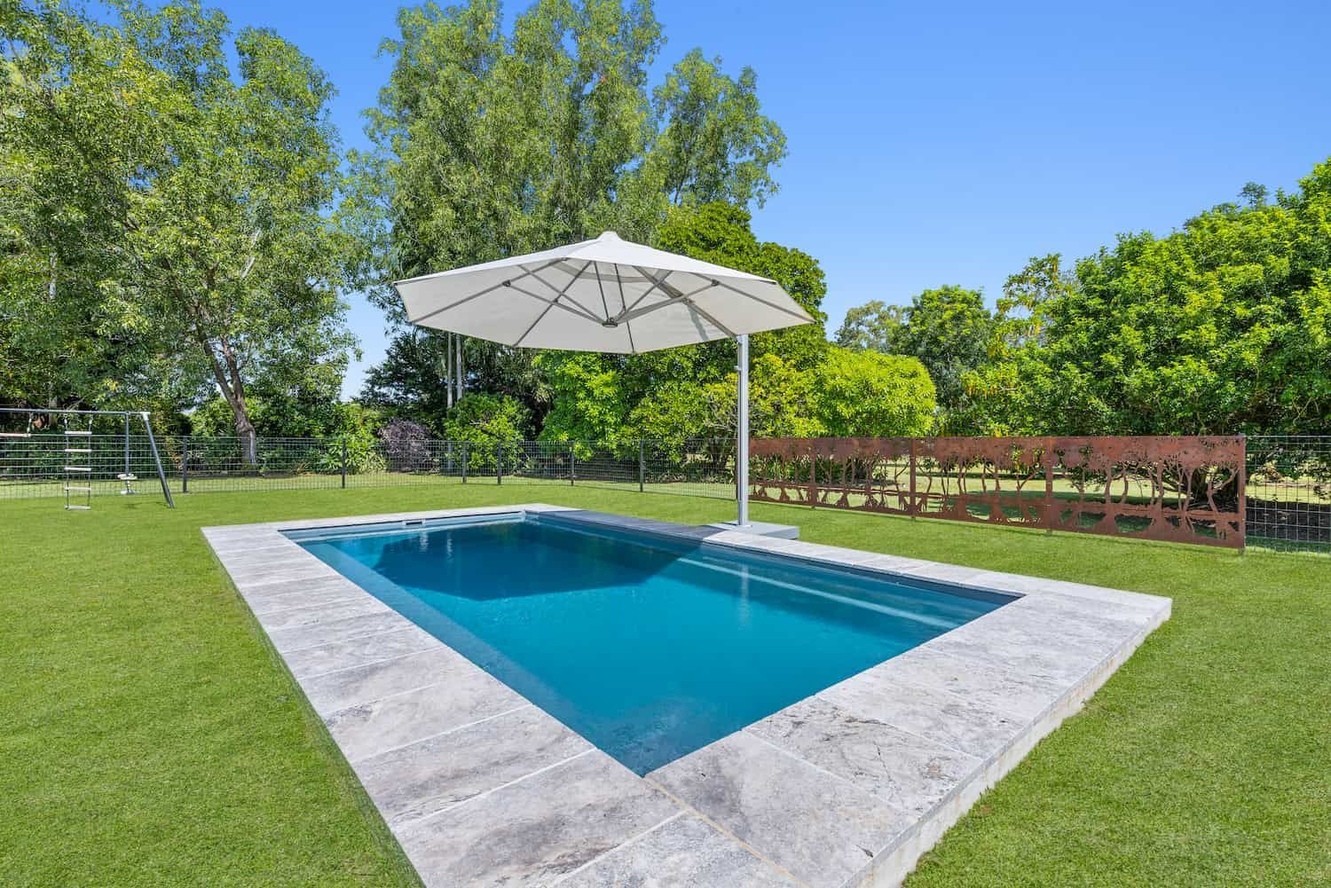 A Swimming Pool With a White Umbrella in the Middle of It — Pooltech NT In Alawa, NT