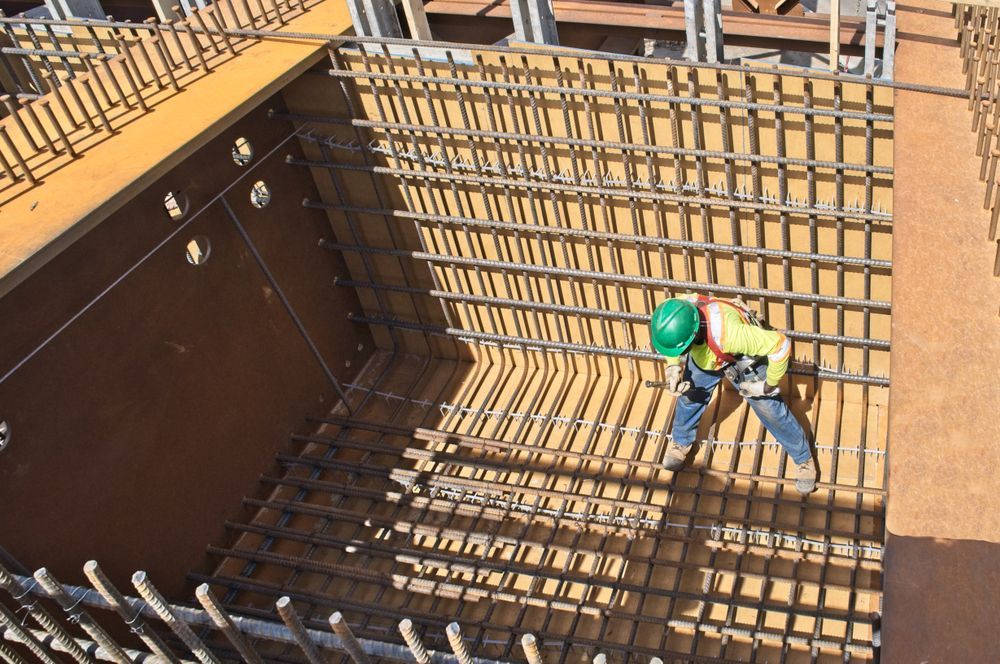 Construction Worker in Green Hard Hat Working on Rebar Framework — BC Earthmoving & Civil Construction in East Barron QLD
