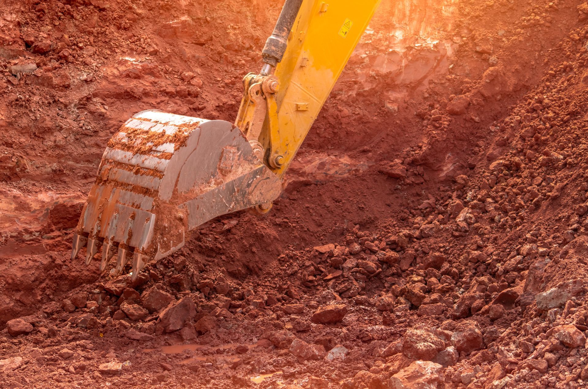 Yellow Excavator Bucket Digging Into Red Soil — BC Earthmoving & Civil Construction in East Barron QLD
