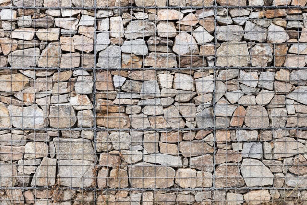 Stone Wall Held in Place by a Metal Wire Grid — BC Earthmoving & Civil Construction in East Barron QLD
