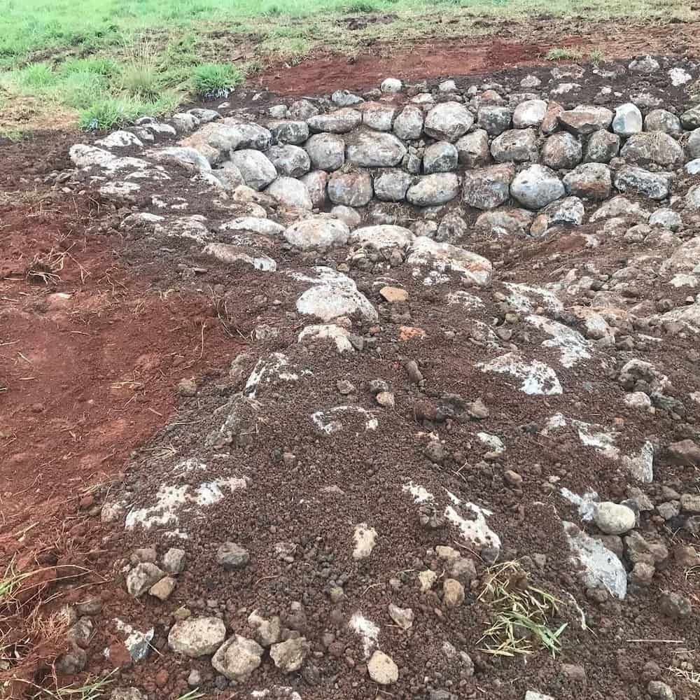Stone Wall Being Constructed With Surrounding Red Dirt and Grass — BC Earthmoving & Civil Construction in East Barron QLD
