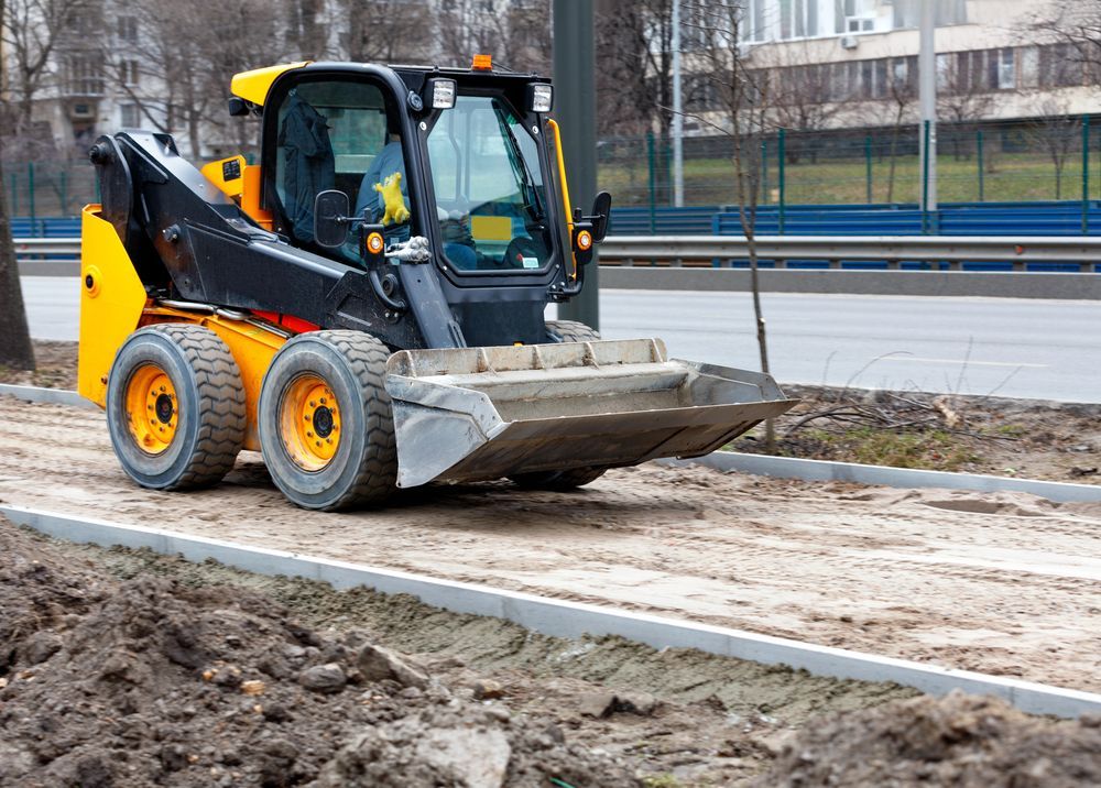 Yellow and black skid steer loader on dirt road, prepping a sidewalk — BC Earthmoving & Civil Construction in East Barron QLD