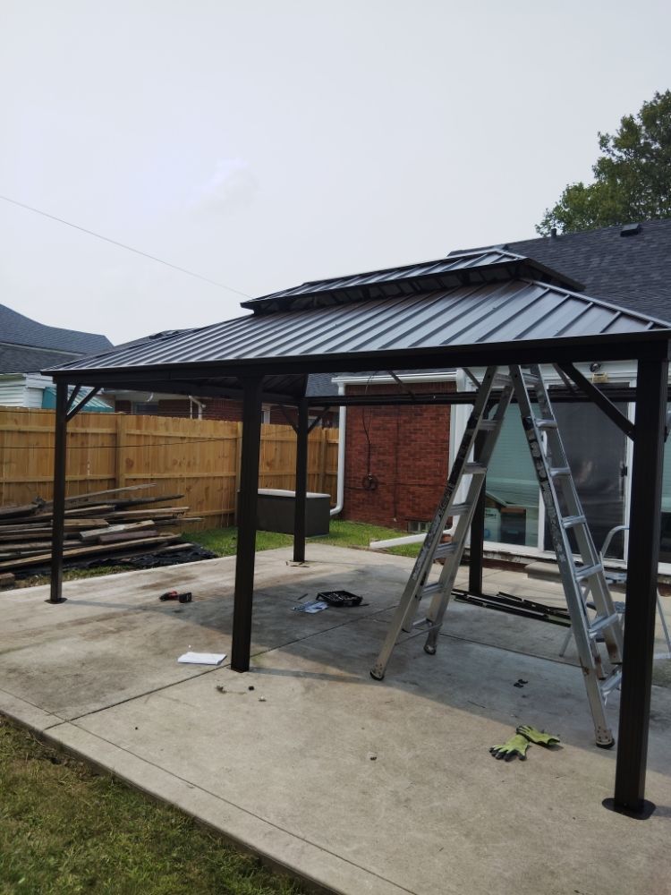 Woman in straw hat smiles, holding wine glass near a lake.