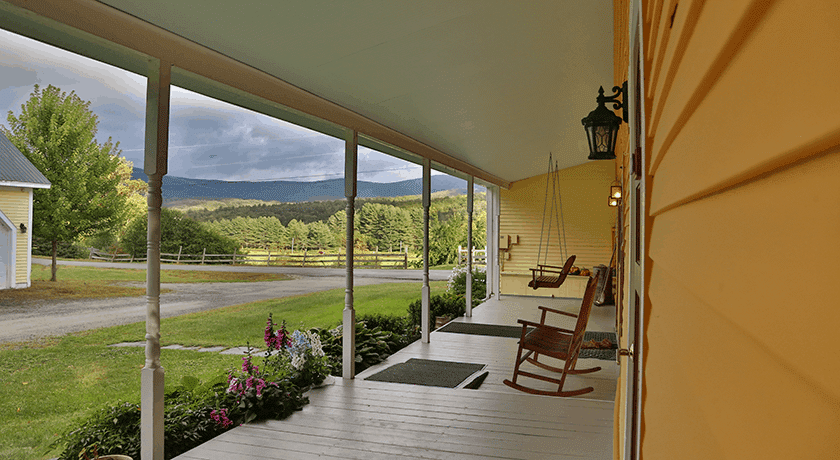 A porch with rocking chairs and a swing on it