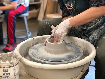 A person is making a pot on a pottery wheel.