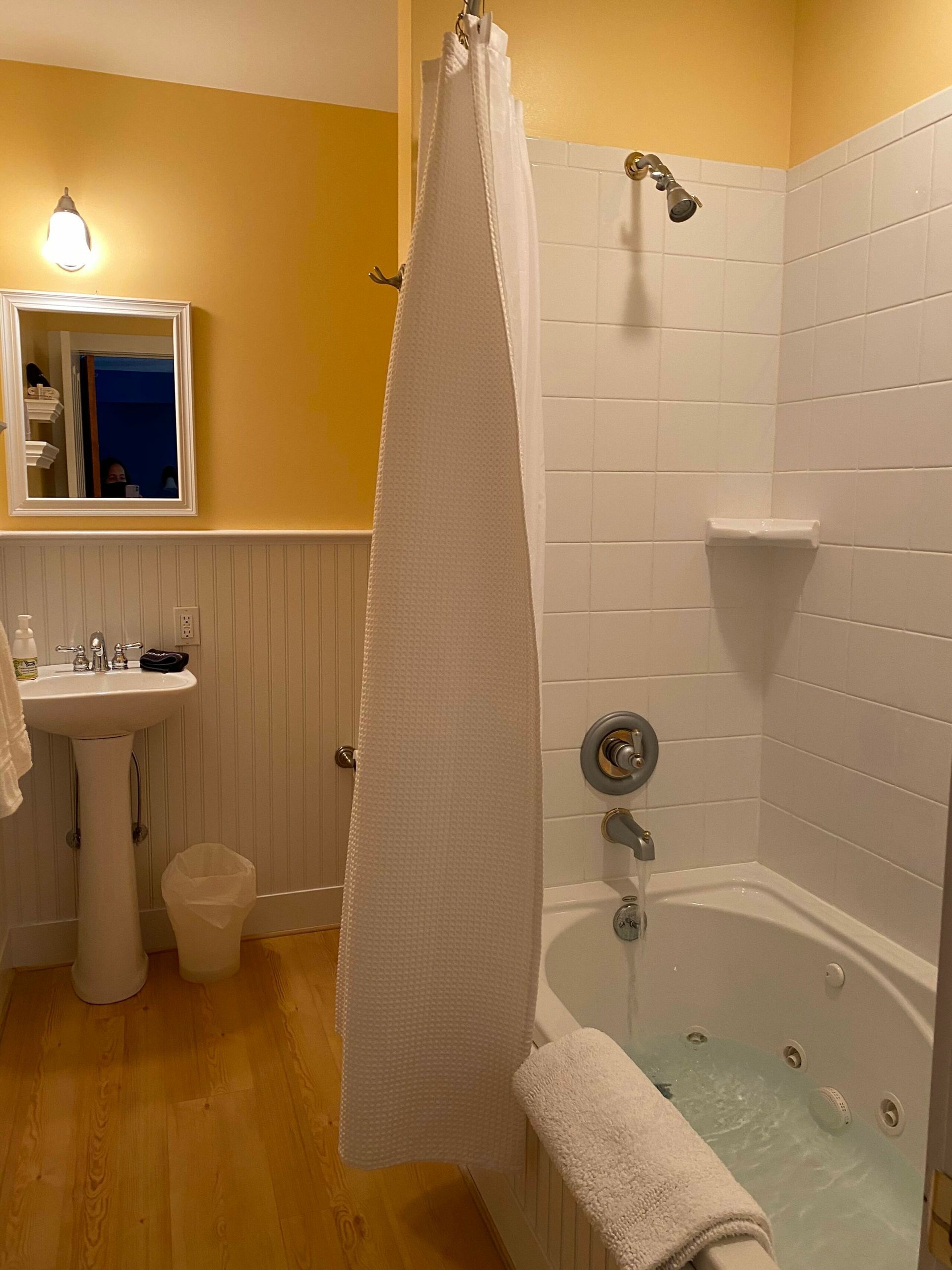 A bathroom with a tub , sink , mirror and shower.