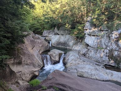 A waterfall is surrounded by rocks and trees in the middle of a forest.