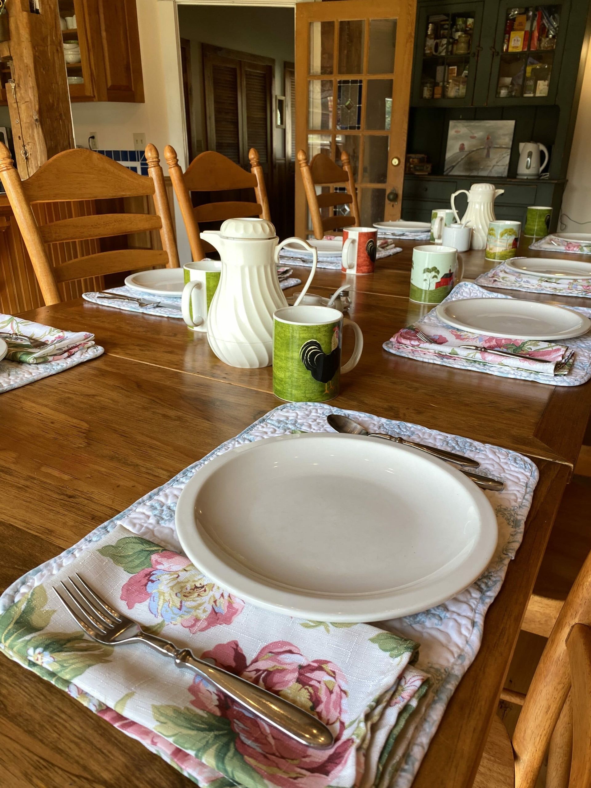 A dining room table with plates , cups , and napkins on it.