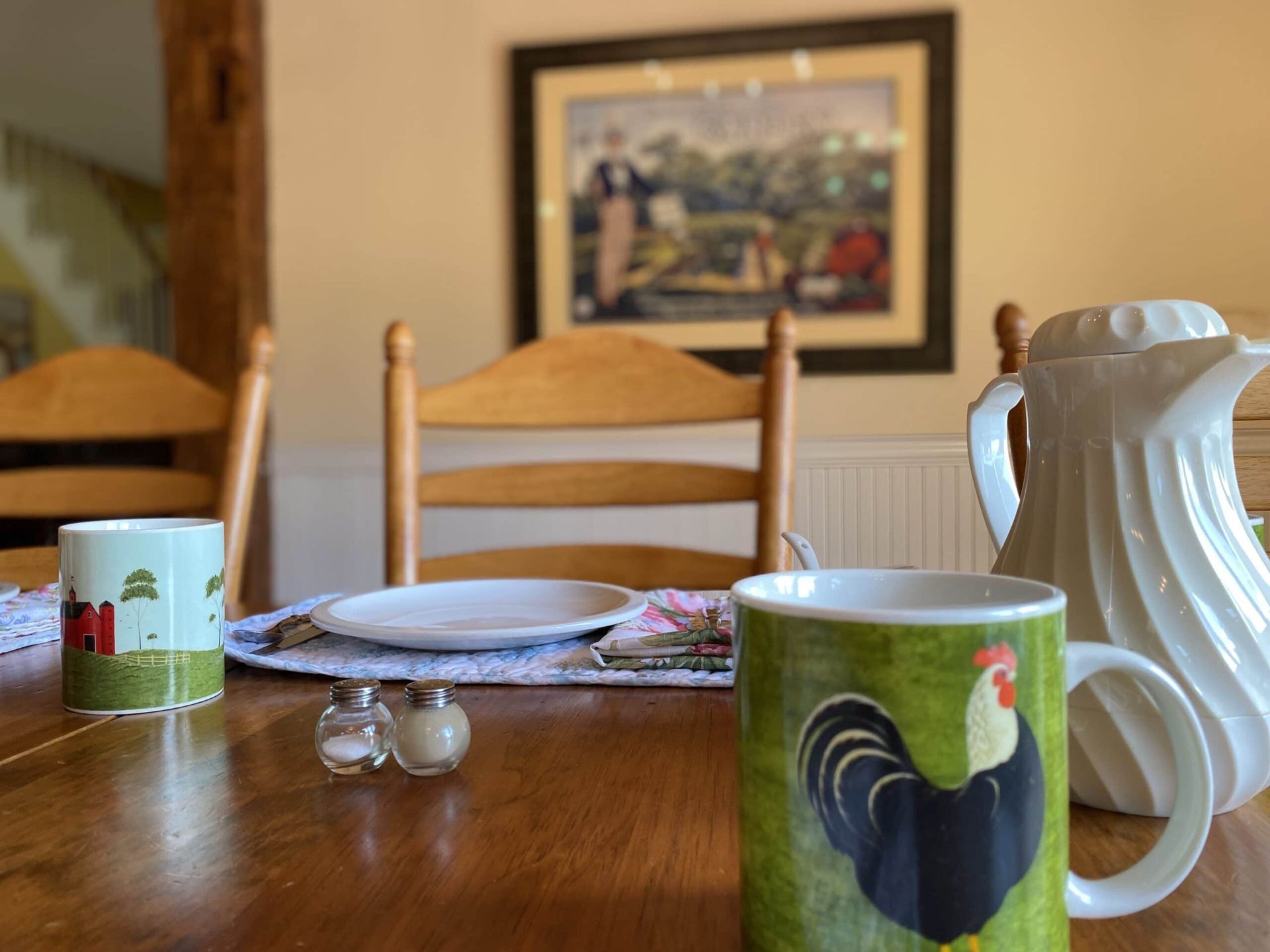 A green mug with a rooster on it sits on a wooden table.