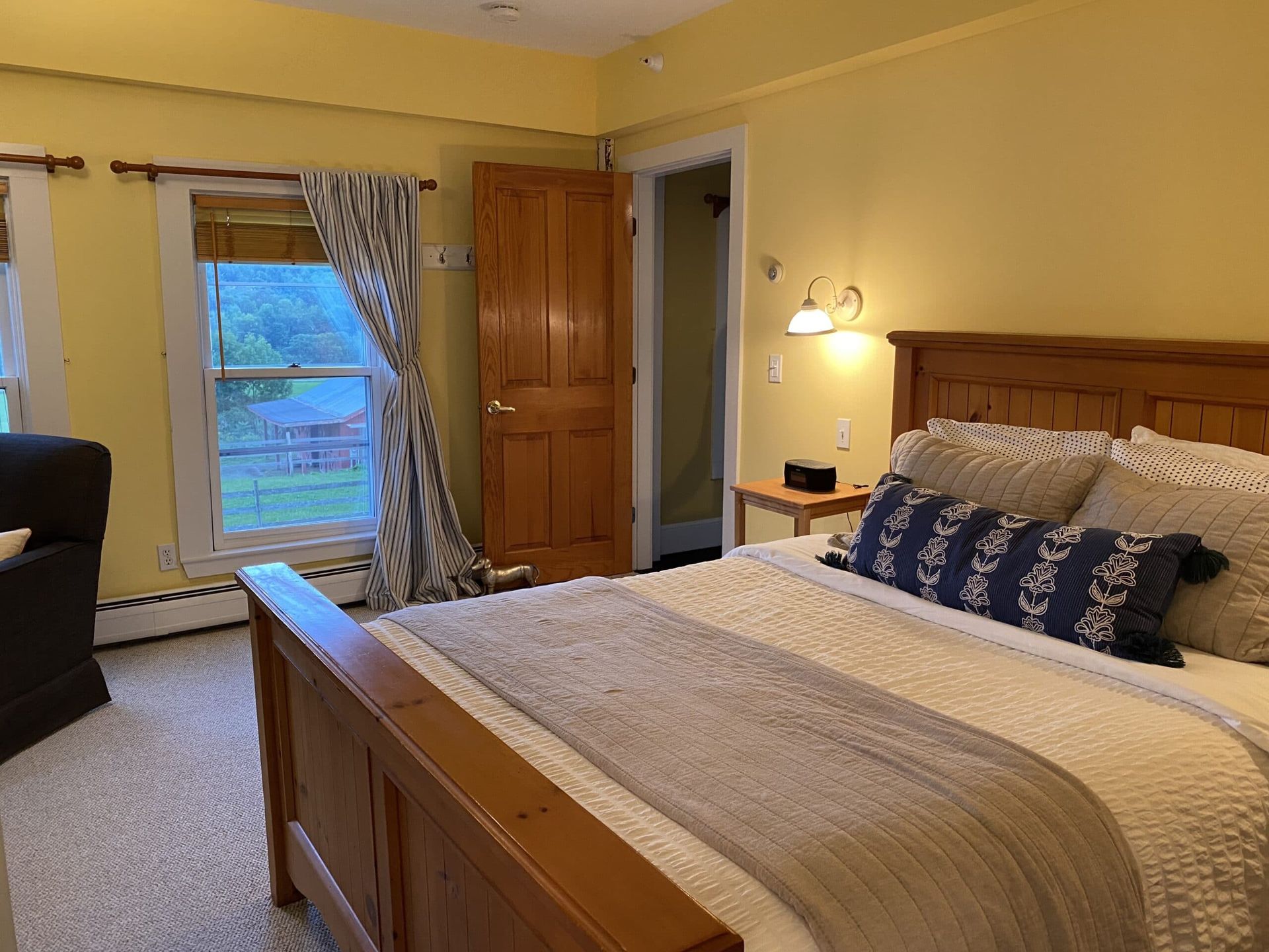 A bedroom with a king size bed , a chair , and a window.