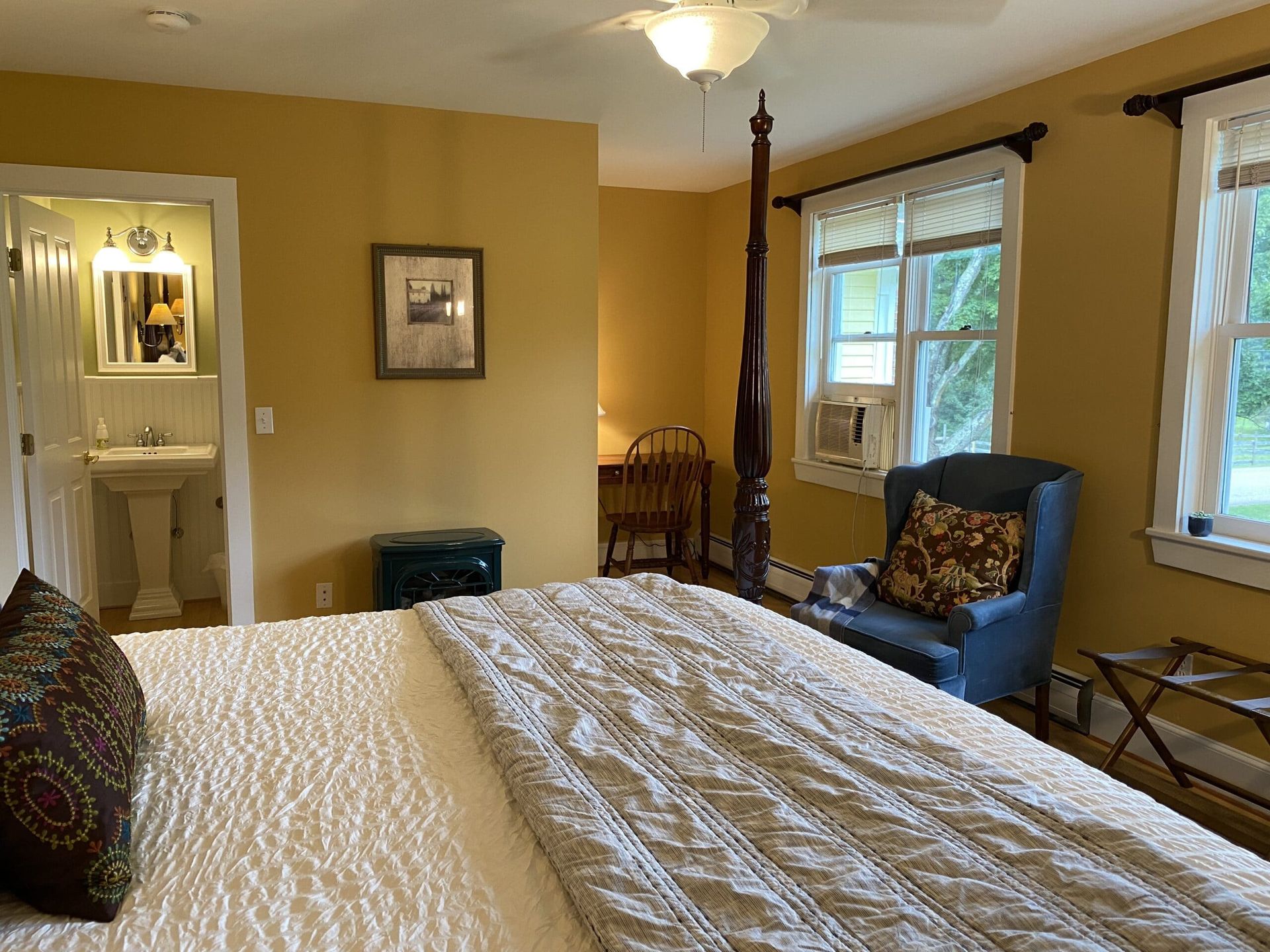 A bedroom with a king size bed , chair , desk and sink.
