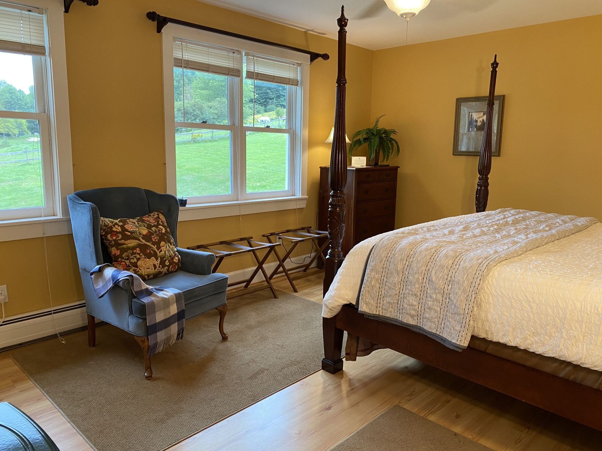 A bedroom with a four poster bed , chair and window.