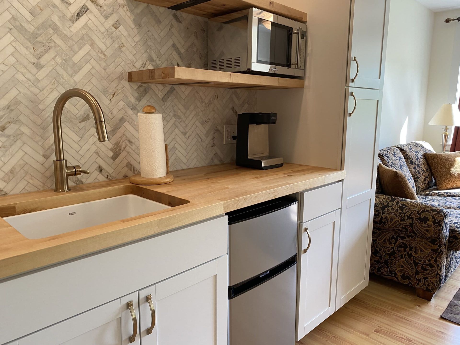 A kitchen with a sink , refrigerator , microwave and coffee maker