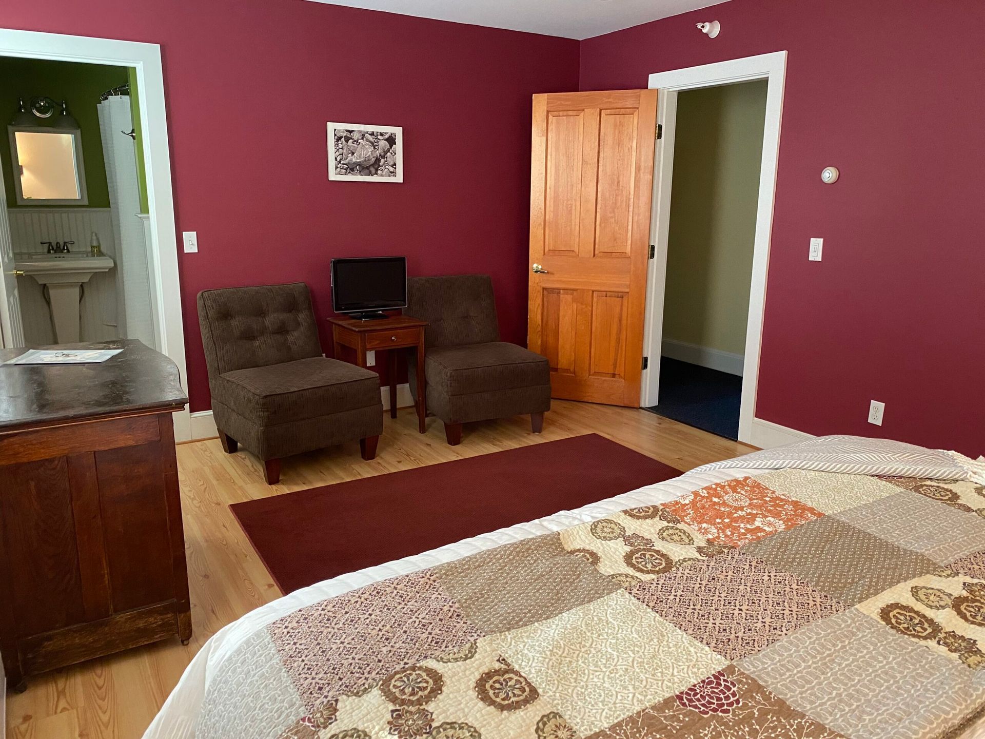 A bedroom with a bed , two chairs , a dresser and a television.
