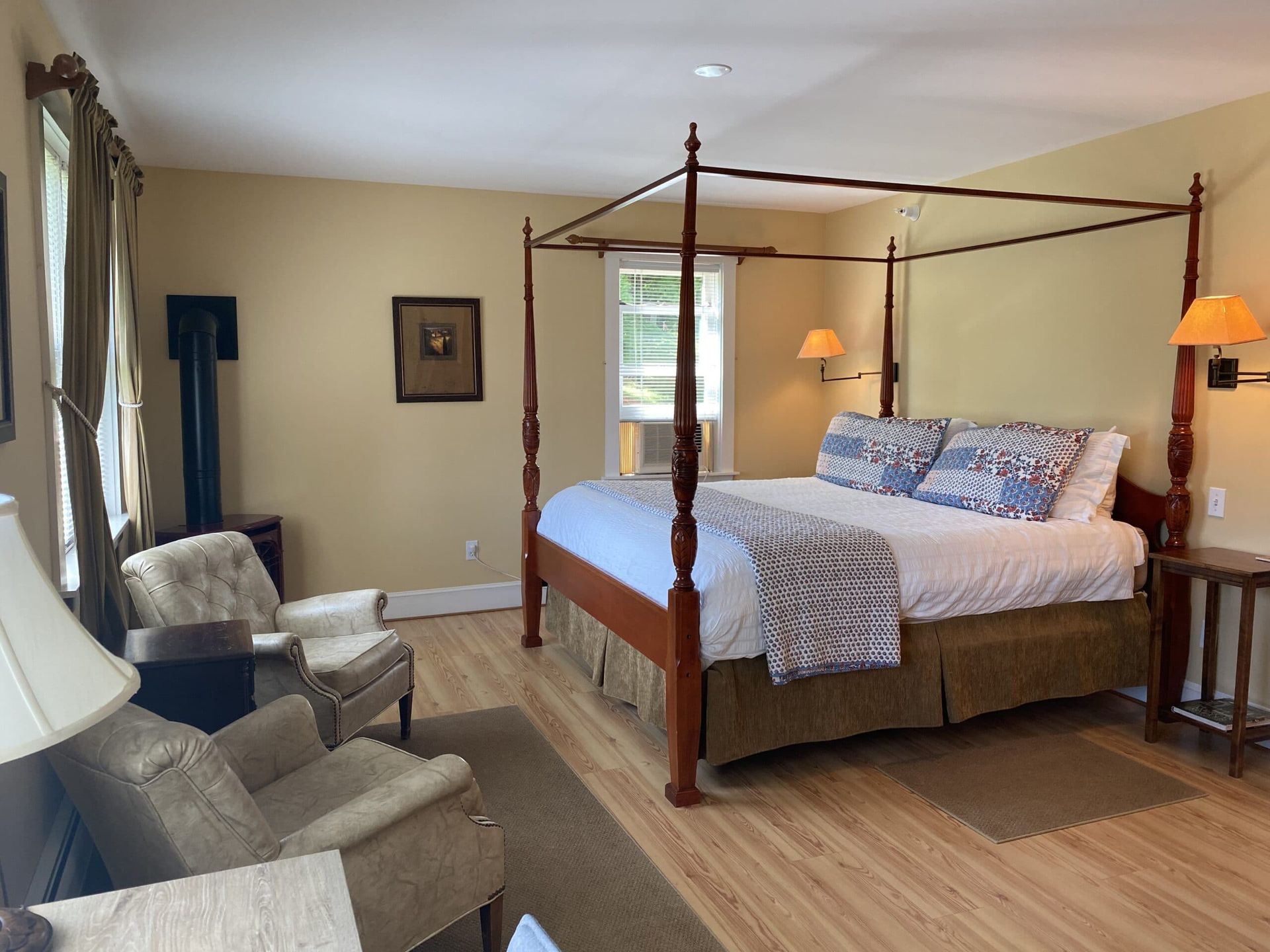 A bedroom with a four poster bed and chairs