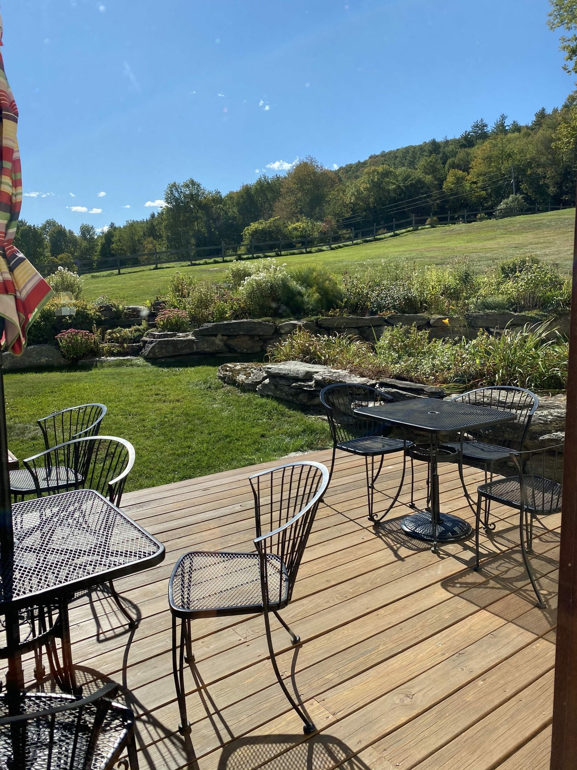 A wooden deck with tables and chairs and an umbrella.