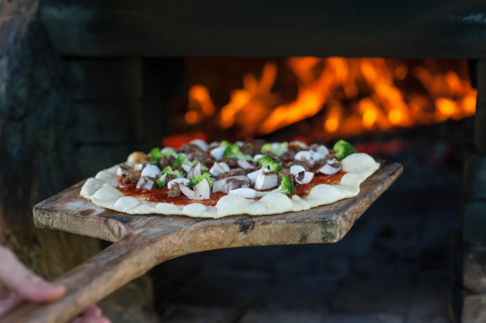 A pizza is being thrown out of a wood oven