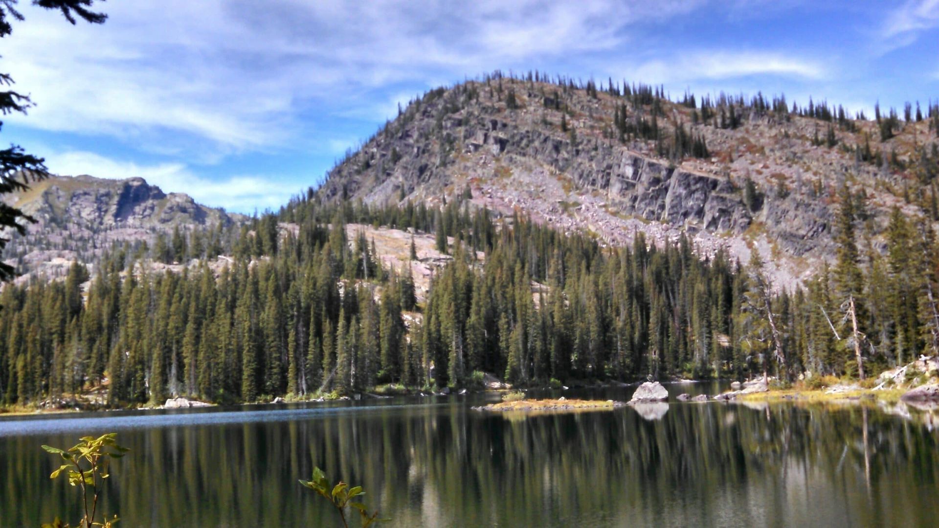 A lake surrounded by trees and mountains with a mountain in the background.