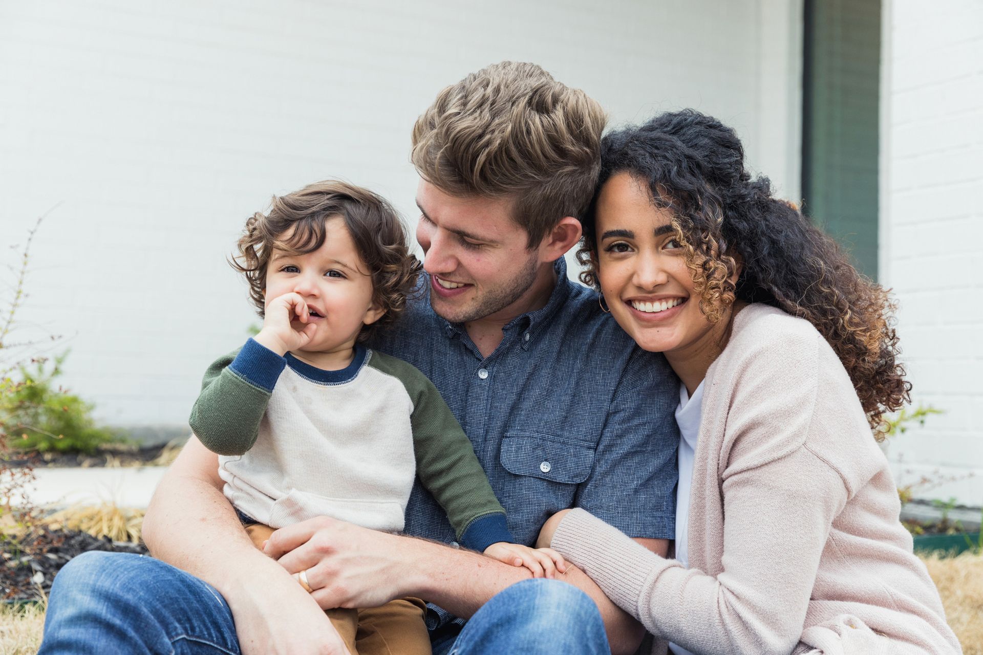 A man and woman are sitting on the ground with a child.