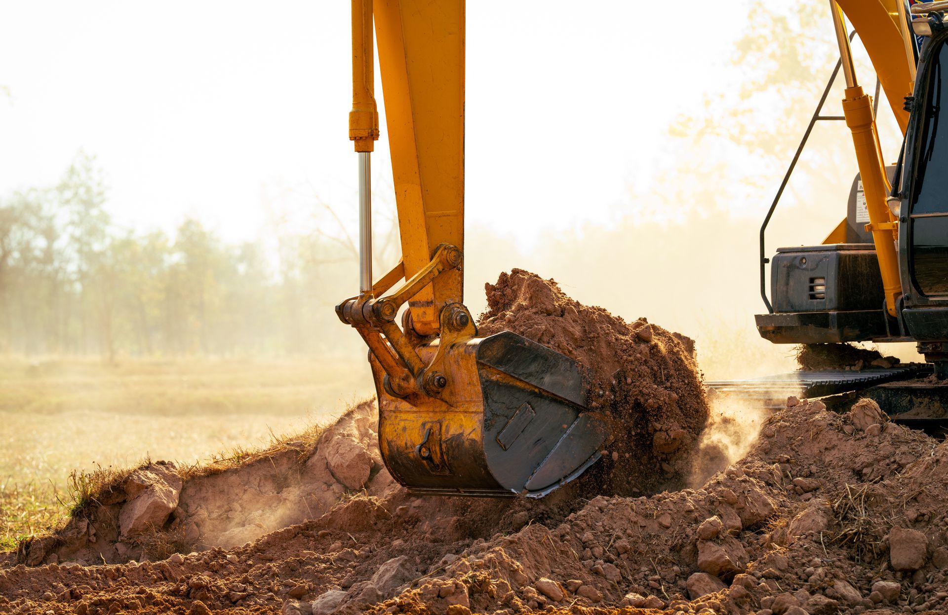 Yellow excavator digging in brown soil on a sunny day.