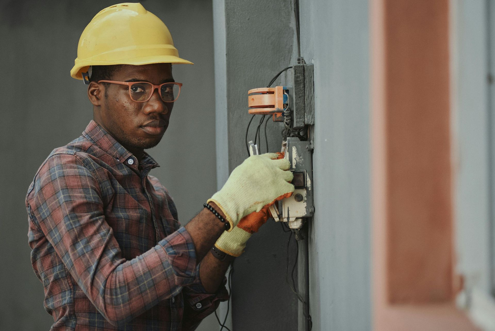 A man wearing a hard hat and gloves is working on a wall.