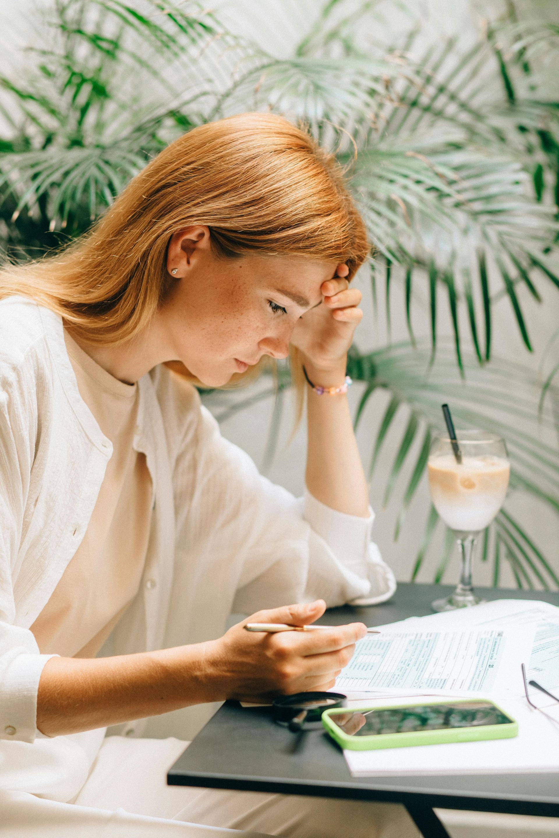 A woman is sitting at a table looking at her phone.