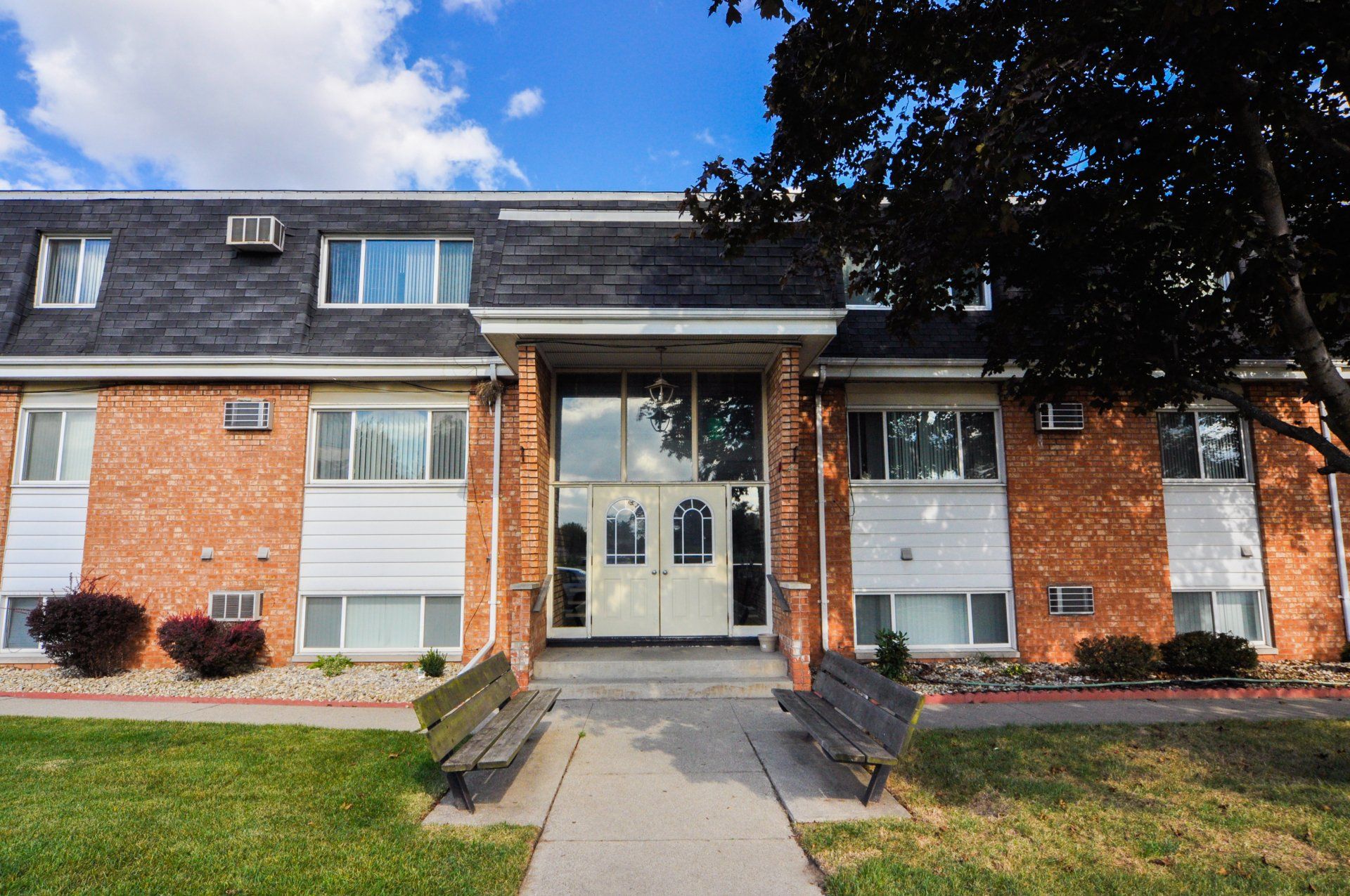 A brick building with a white door and a bench in front of it
