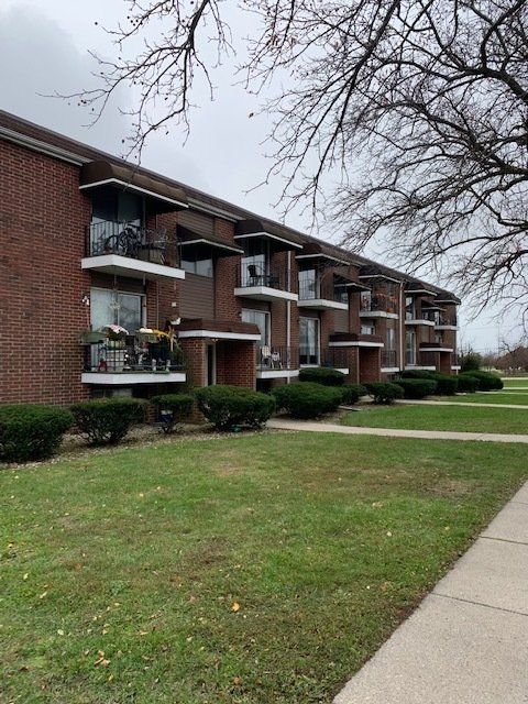 A row of apartment buildings with balconies and a sidewalk in front of them