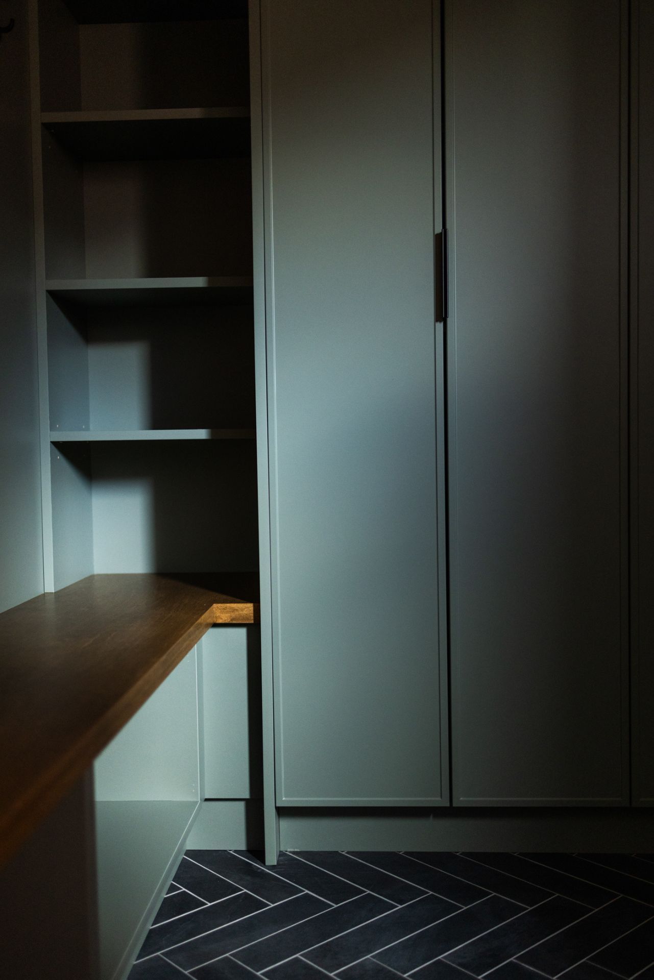 Built-in storage unit with shelves and cabinet, brown counter, and patterned dark blue floor.