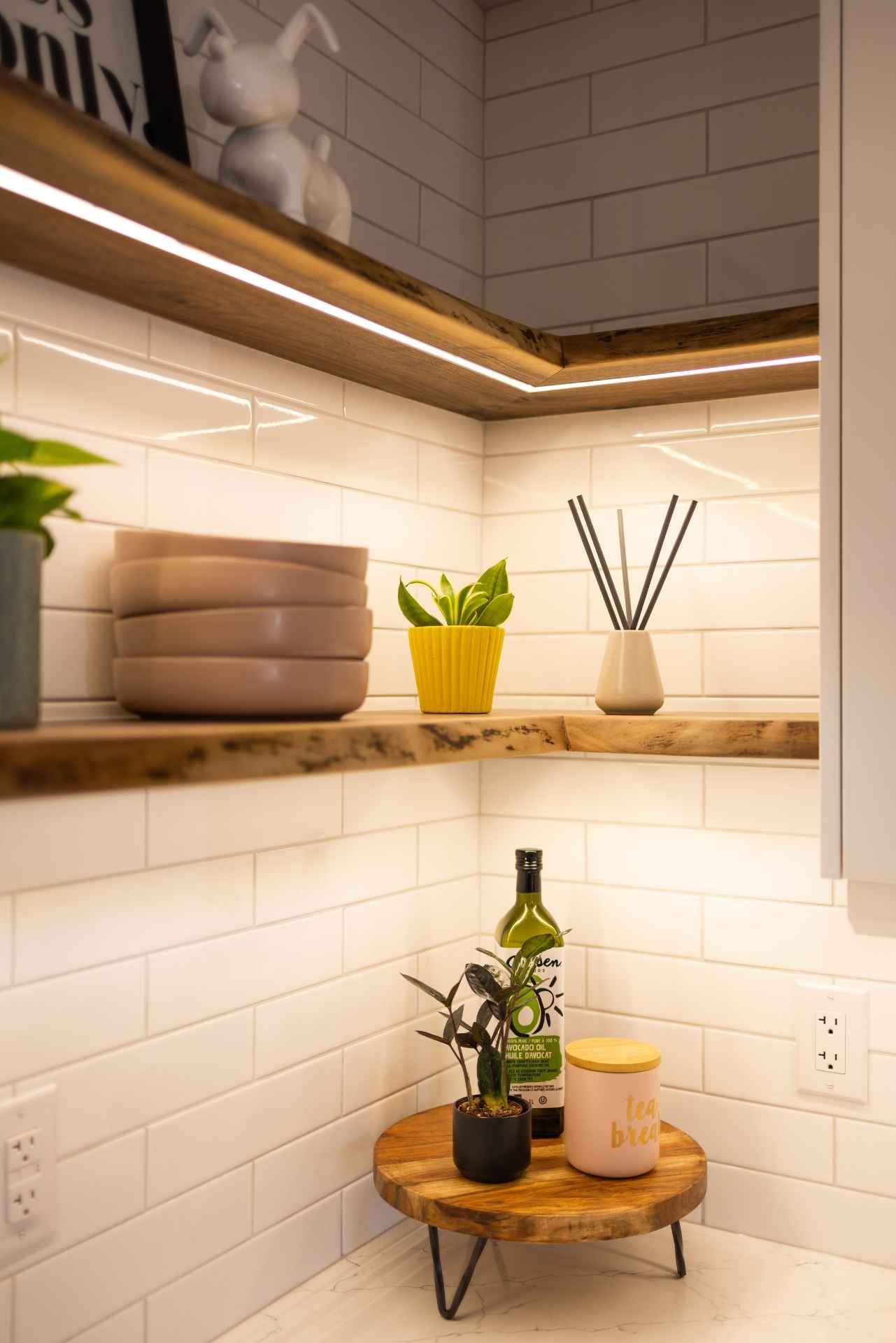 Wooden shelves with plants, dishes, and bottles, illuminated by LED lights against white tile.