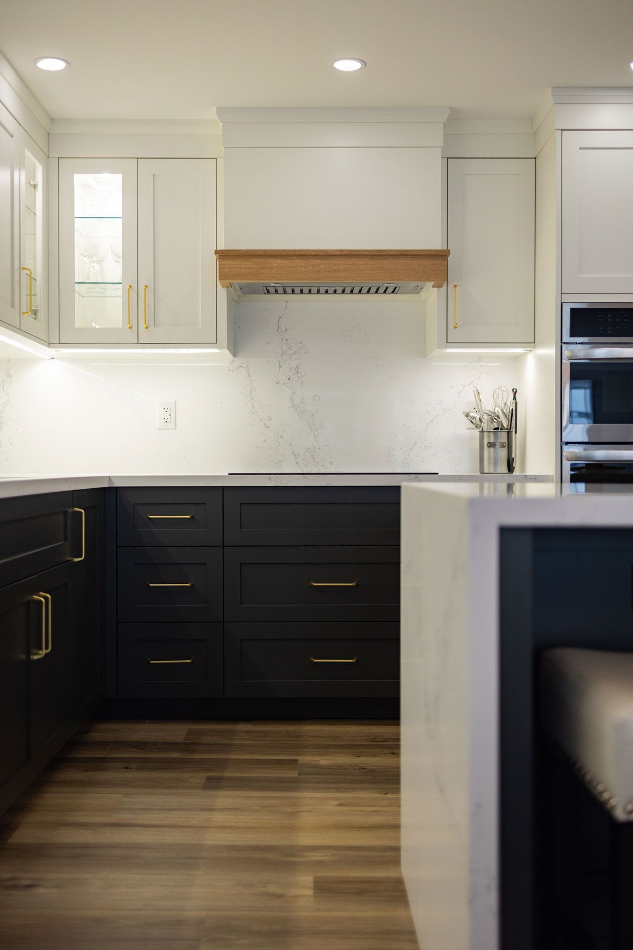 Modern kitchen with black lower cabinets, white uppers, and wood accents.