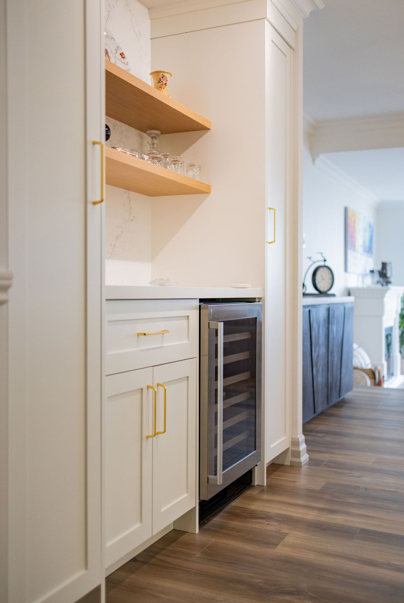Built-in bar area with wine fridge, white cabinets, and open wooden shelves.