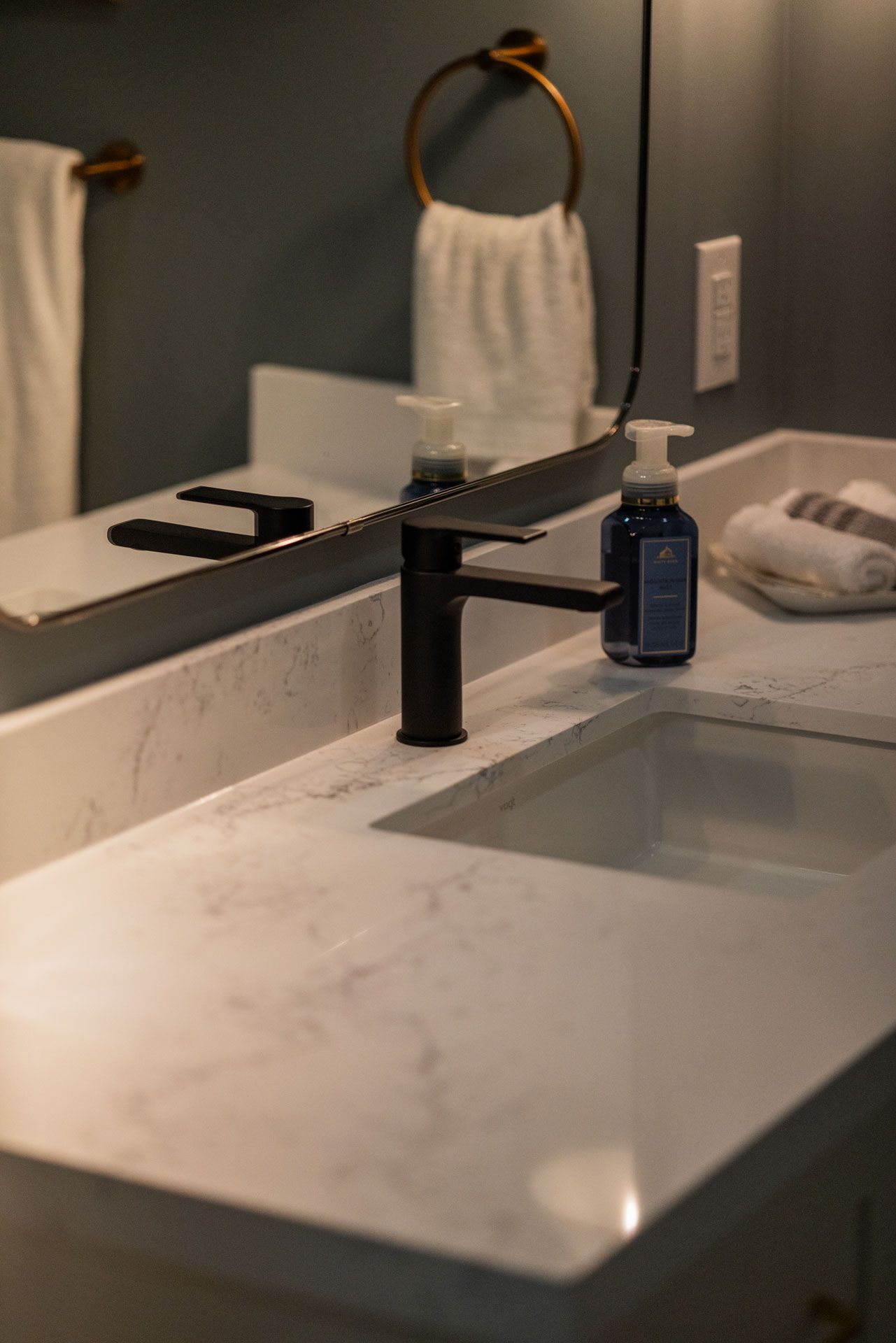 Black faucet and white sink on a marble countertop; bathroom setting.
