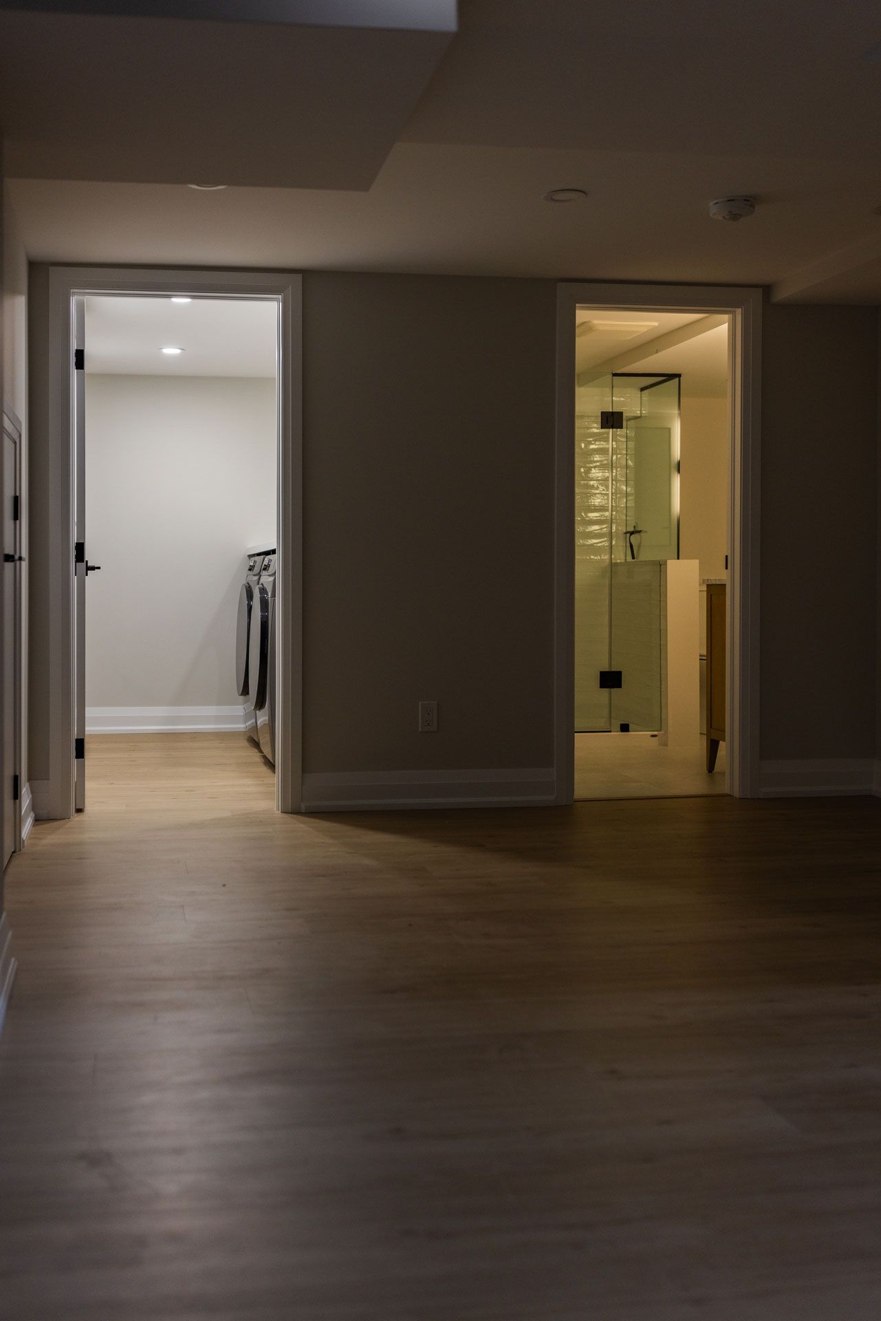 Open doorways to a laundry room and bathroom with wood floors.