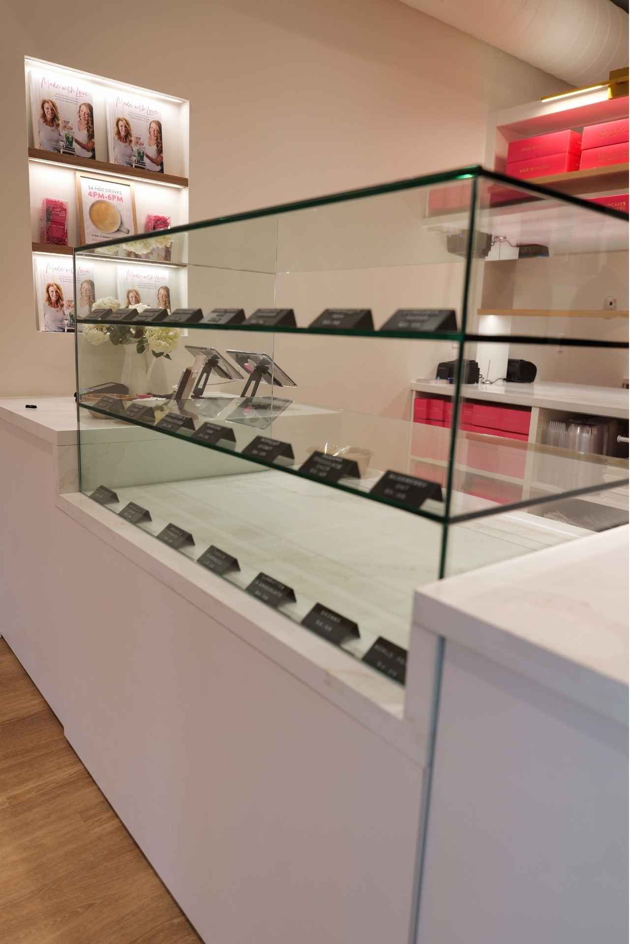 White display case with glass top showcasing chocolates in a bright shop setting.