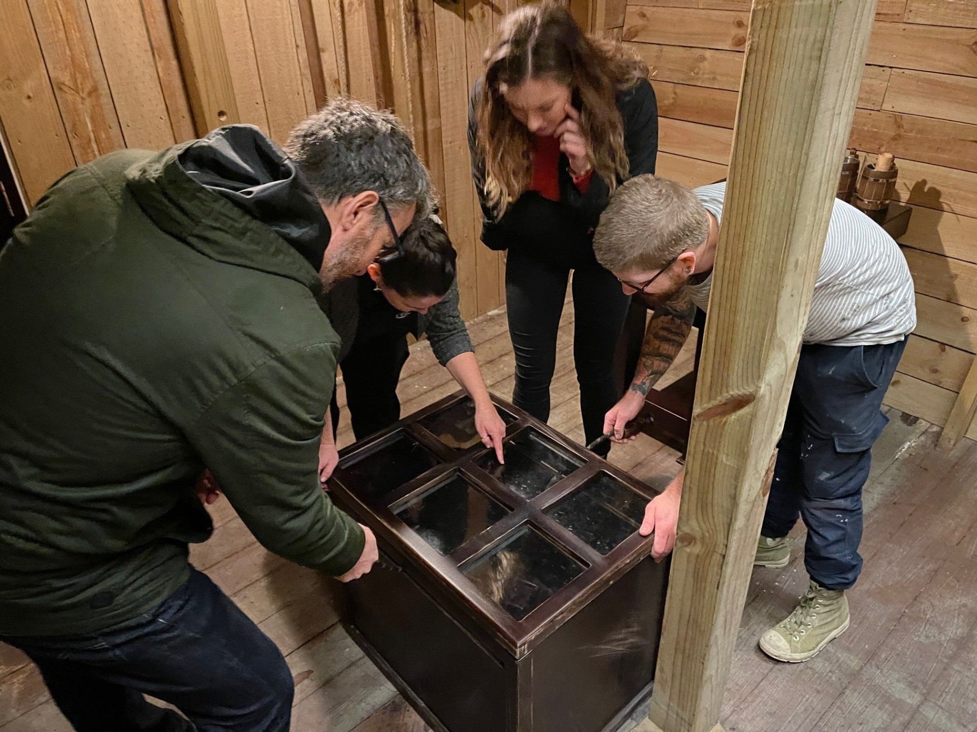 A group of coworkers excitedly huddled around an escape room puzzle