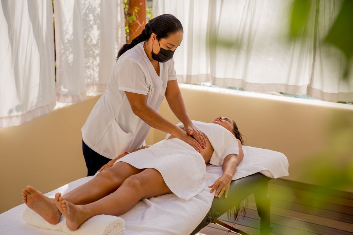 Terapeuta de masaje realizando un masaje abdominal a una persona tumbada en una camilla de masaje.