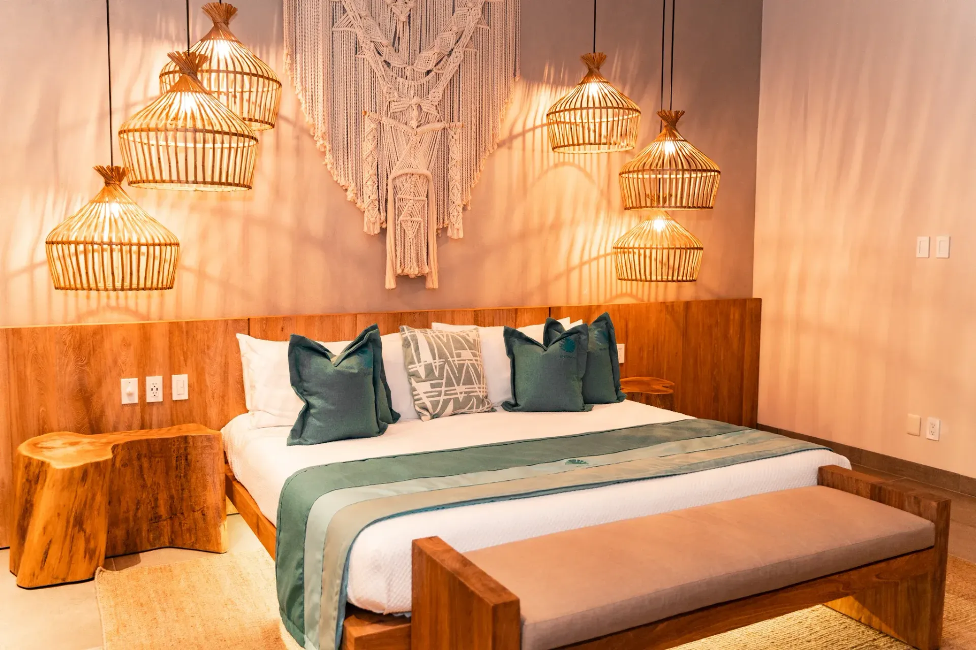 Dormitorio con cama de madera, lámparas colgantes de mimbre, decoración de pared de macramé, detalles en color verde .
