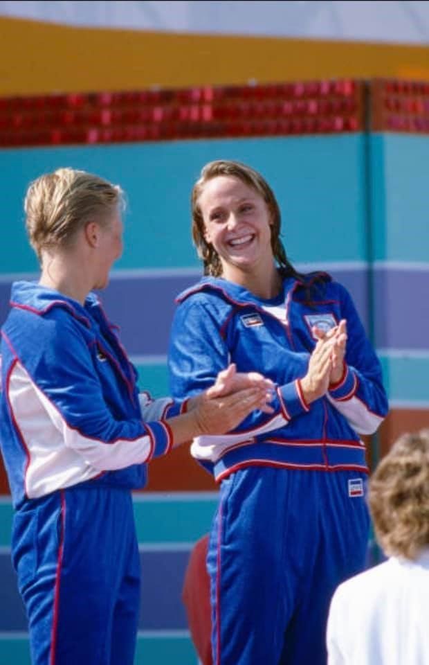 Two women in blue jumpsuits are clapping each other